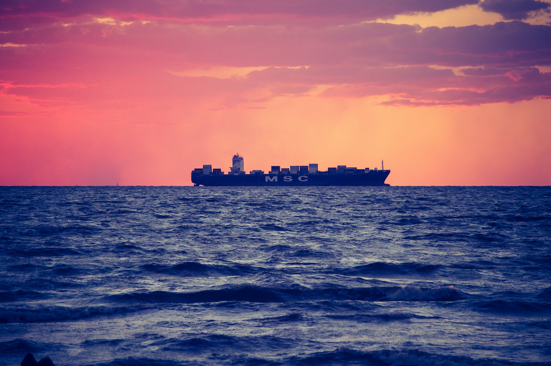 Container ship crossing open sea at dusk